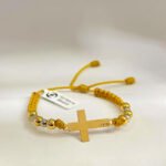 PULSO TEJIDO CON HERRAJE CRUZ Y 10 BALINES DE ORO 18K ESTILO MACRAMÉ EN HILO COLOR MOSTAZA