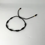 PULSO TEJIDO CON 7 NUDOS EN COLOR NEGRO CON 2 BALINES DE ORO 18K